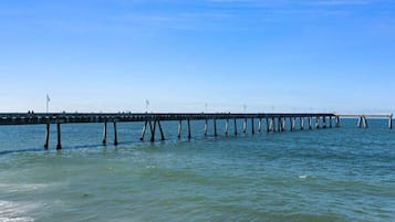 A pier extending into calm water with a clear sky above.
