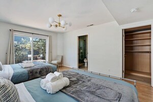 A hotel room with two beds, a large window, a bathroom, and a wardrobe.