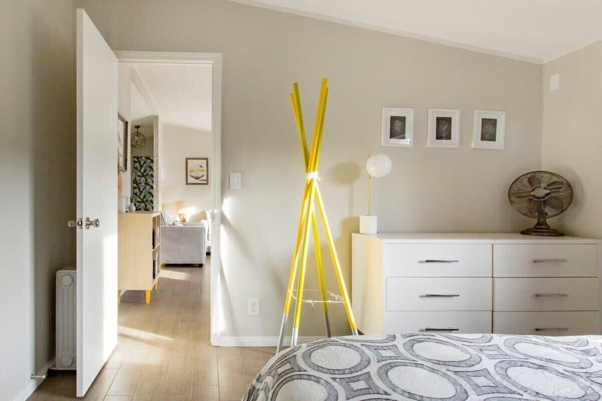 A bedroom with a bed, a bedside table, a dresser, and a lamp.