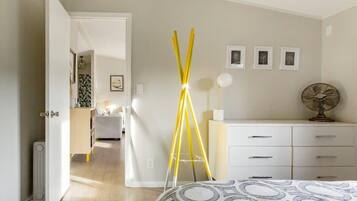 A bedroom with a bed, a bedside table, a dresser, and a lamp.