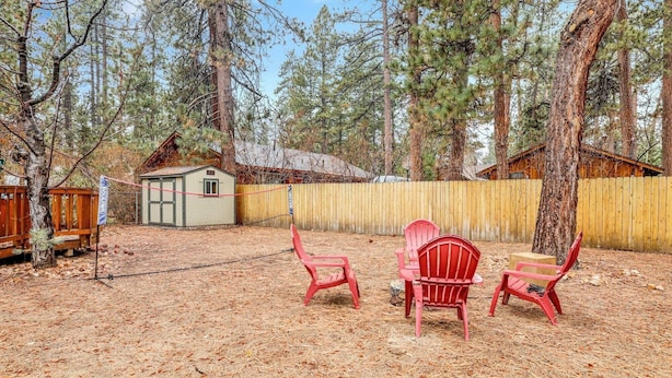 A backyard with a wooden deck, a small shed, and red Adirondack chairs. - Timber Pines Chalet #2417 (Big Bear Lake)