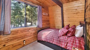 A wooden cabin room with a bed, a window, and a sign that reads 'Sweets Dreams'.