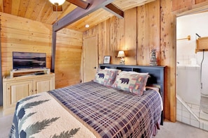 A bedroom with a bed, a television, and wooden walls. - Wolf Cub Cabin#1946 (Big Bear Lake)