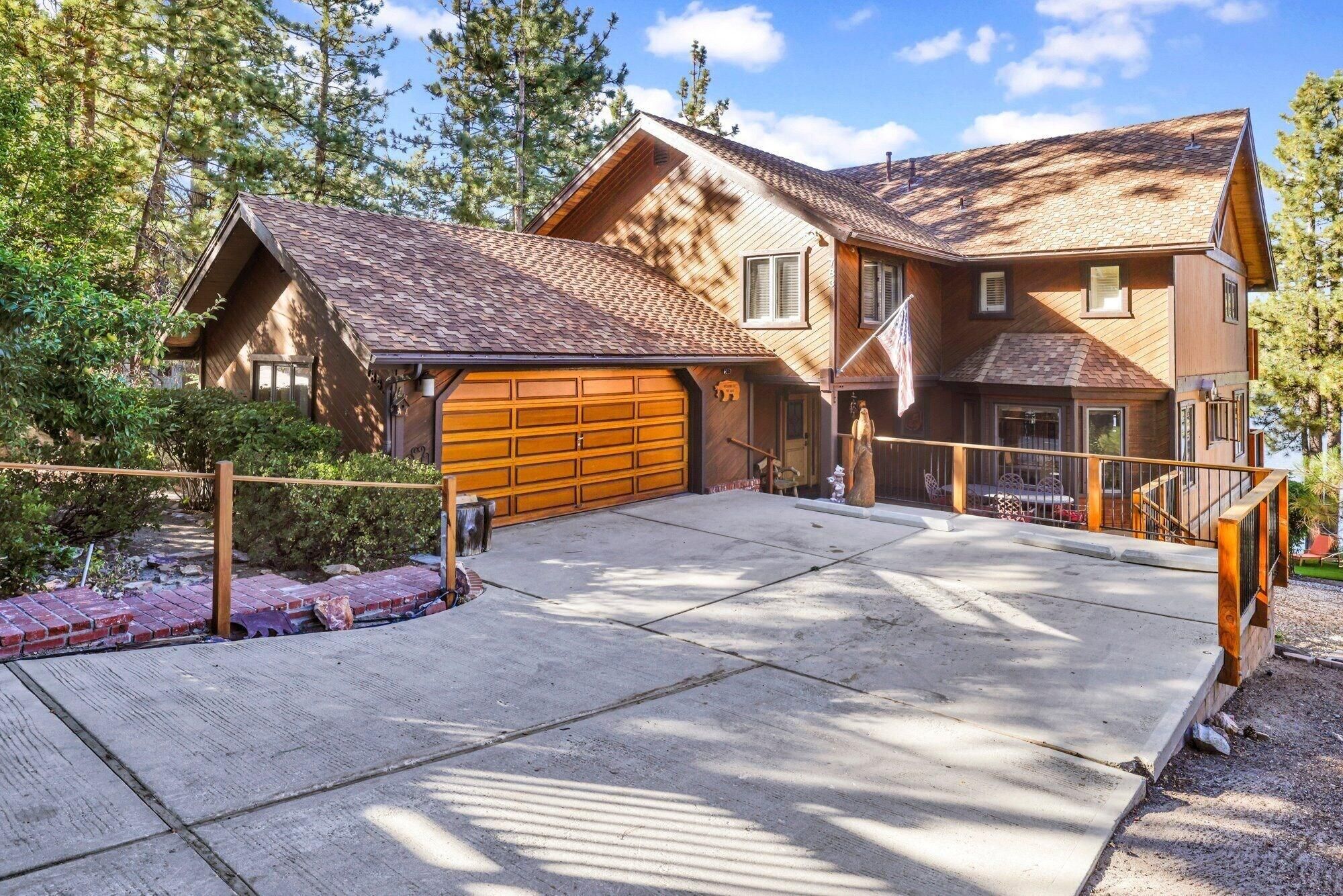A two-story house with a large garage, a covered porch, and a stone driveway.