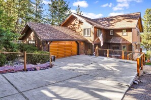 Una casa a due piani con un ampio garage, un portico coperto e un vialetto in pietra.