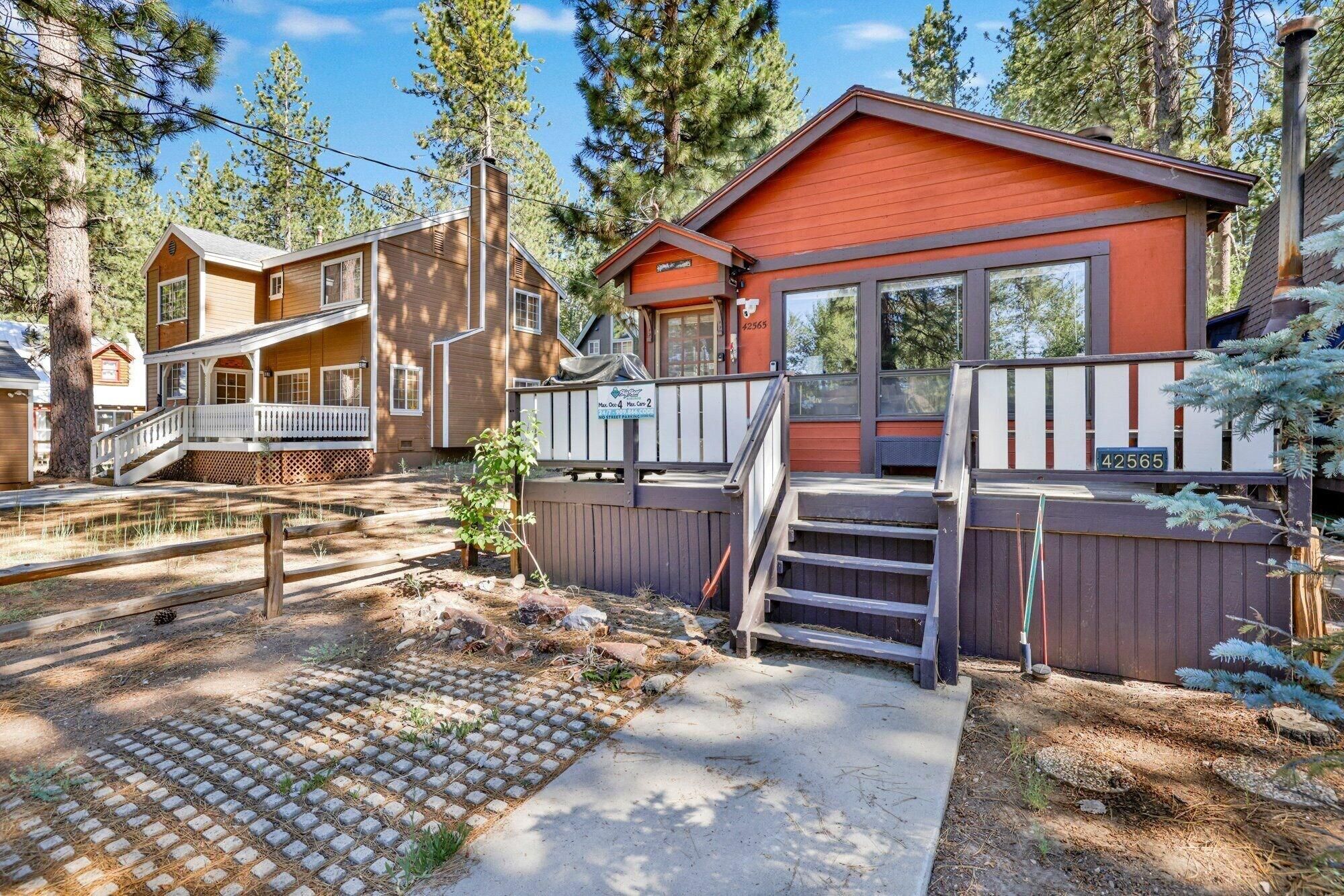 A cabin with a wooden exterior, a porch, and a deck.