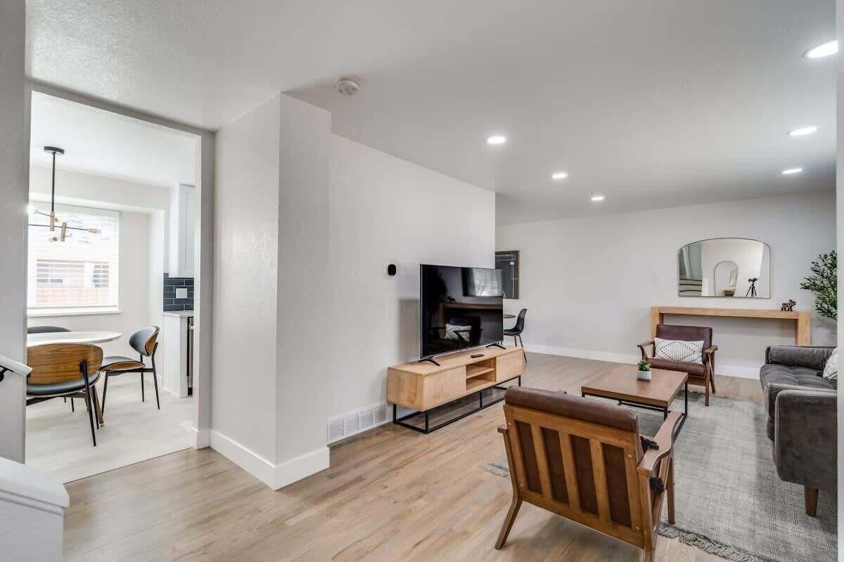 A modern living room with a flat-screen TV, wooden furniture, and a fireplace.