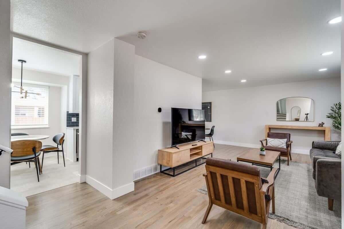 A modern living room with a flat-screen TV, wooden furniture, and a fireplace.
