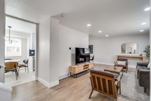 Uma sala de estar moderna com televisão de tela plana, móveis de madeira e lareira.