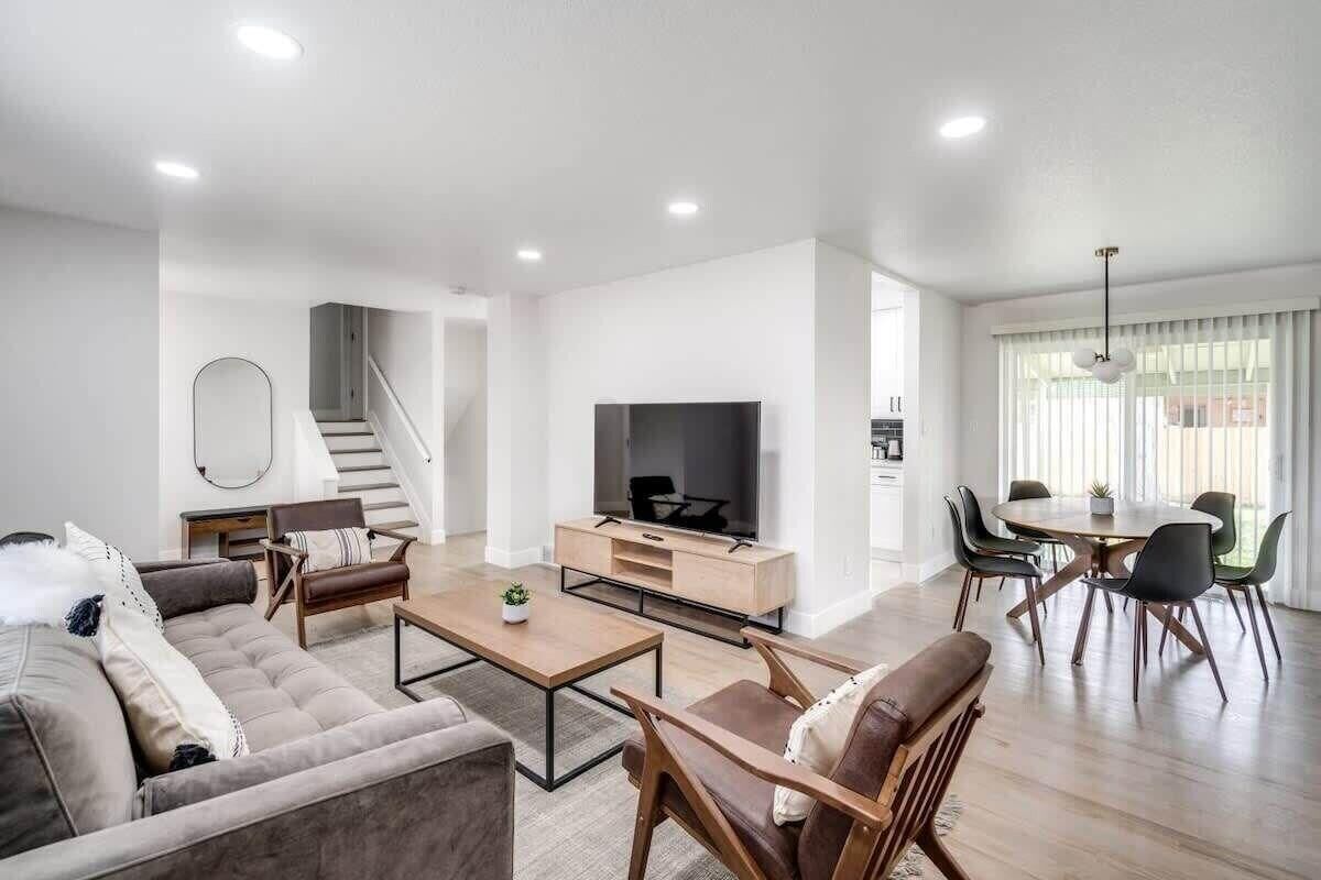 A modern living room with a sofa, coffee table, TV, and dining area.