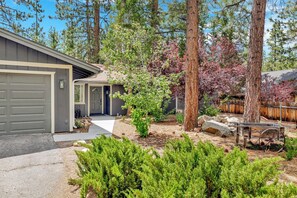 A residential property with a garage, a covered entryway, and a landscaped yard with trees and shrubs. - Wildwood Lodge #2087 (Big Bear Lake)