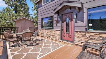 A house with a red door, stone wall, and a deck with wicker furniture.