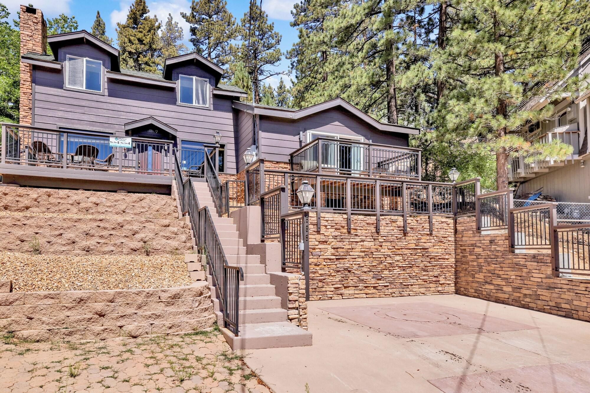 A multi-story building with a stone facade, a staircase leading to a deck, and a view of surrounding trees.