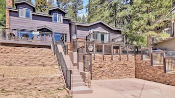 A multi-story building with a stone facade, a staircase leading to a deck, and a view of surrounding trees.