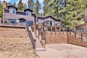 A multi-story building with a stone facade, a staircase leading to a deck, and a view of surrounding trees. - Circle Views #1602 (Big Bear Lake)