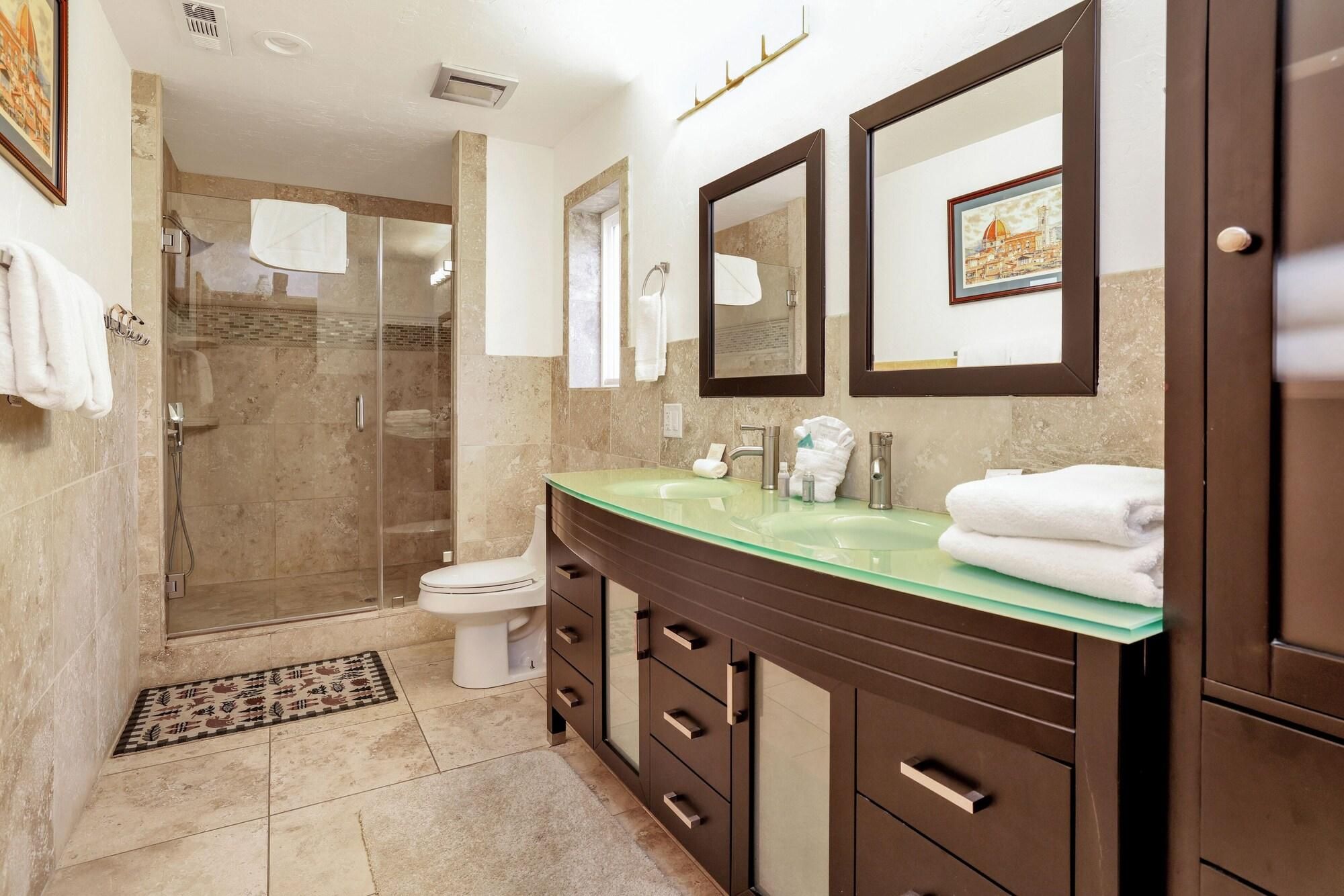 A modern bathroom with a glass sink, a walk-in shower, and a toilet.