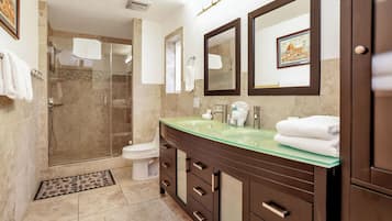 A modern bathroom with a glass sink, a walk-in shower, and a toilet.