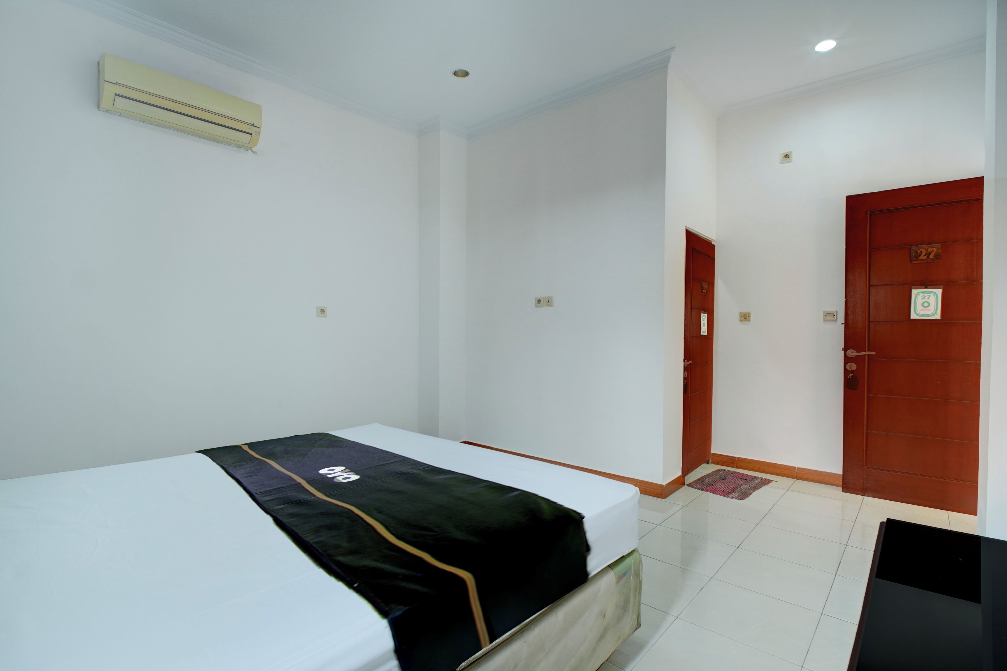 A room with a bed, a door, and a wall-mounted air conditioner.