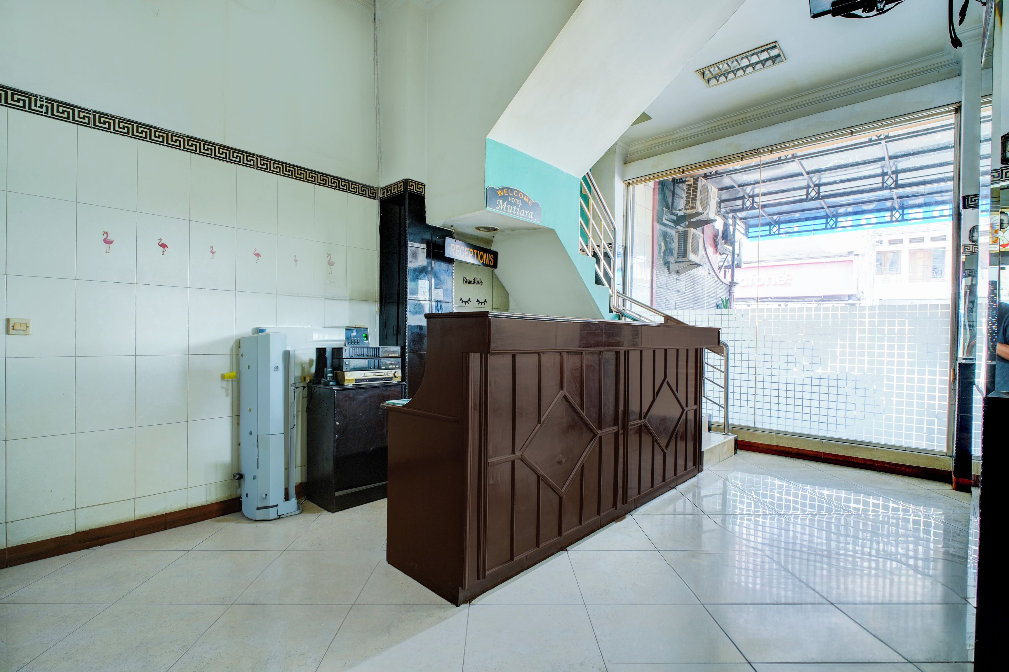 A reception area with a reception desk, a wall-mounted telephone, and a window with a view of the outside.