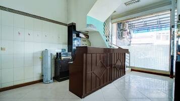 A reception area with a reception desk, a wall-mounted telephone, and a window with a view of the outside.