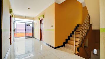 A hotel corridor with a staircase, a door with a sign, and a view of the outside.