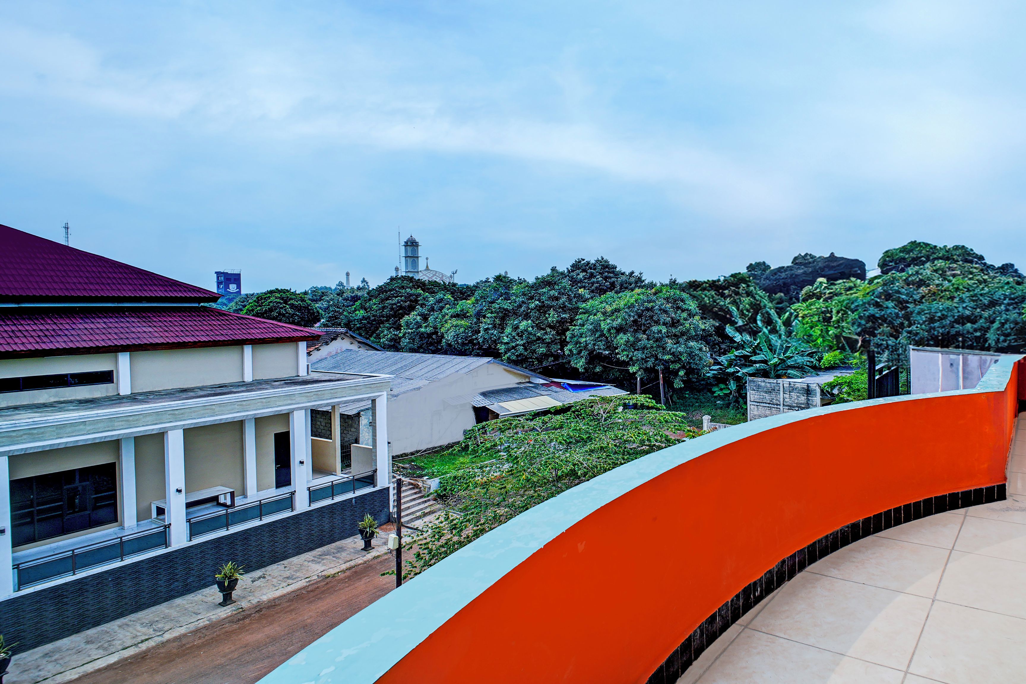 A building with a red roof, a white facade, and a curved orange structure.