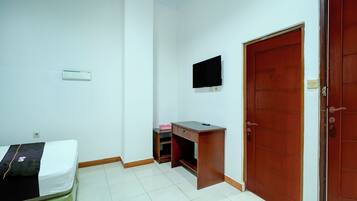 A room with a bed, a desk, a television, and a door.