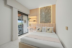 A modern bedroom with a large bed, a headboard with a marble-like design, a desk with a chair, and a view of a car through a sliding door.