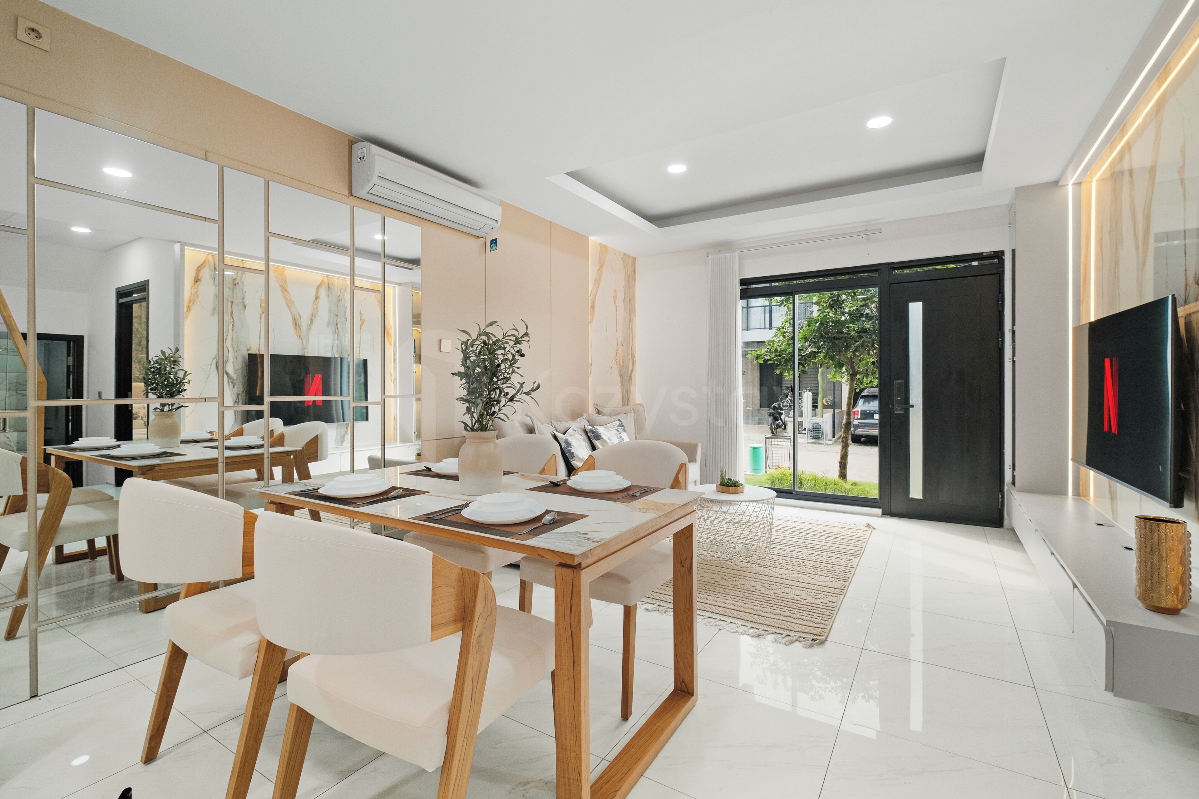 A modern dining area with a wooden table, white chairs, and a large mirror.