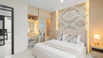 A modern bedroom with a large bed, a bedside table, a nightstand, a mirror, a wardrobe, and a bathroom visible through an open door.