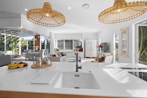 A modern kitchen with a white countertop, double sink, and a dining area with a table and chairs.