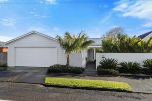 A residential property with a garage, a covered entryway, and a well-maintained front yard with palm trees and shrubs.