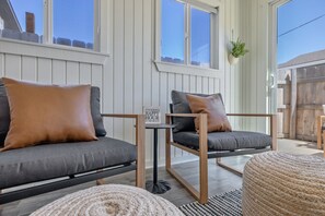 Ein gemütlicher Außenbereich mit zwei Sofas und einem kleinen Tisch, umgeben von Holzwrechen und einem Holzzaun.