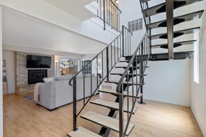 A modern interior with a staircase, a fireplace, and a living area with a sofa. - Sandpiper Dune Escape - Steps to the Beach & Dunes - 5 Bedrooms (Oceano)
