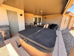 Un espace extérieur abrité, avec une table et des chaises, une poubelle et un barbecue.