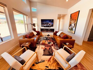 A modern living room with leather sofas, a flat-screen TV, and a fireplace.
