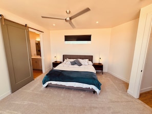 A bedroom with a bed, two bedside tables, a ceiling fan, a window, and a sliding door.