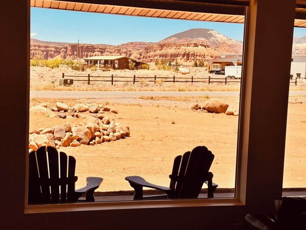 A room with two chairs facing a large window overlooking a desert landscape with mountains.
