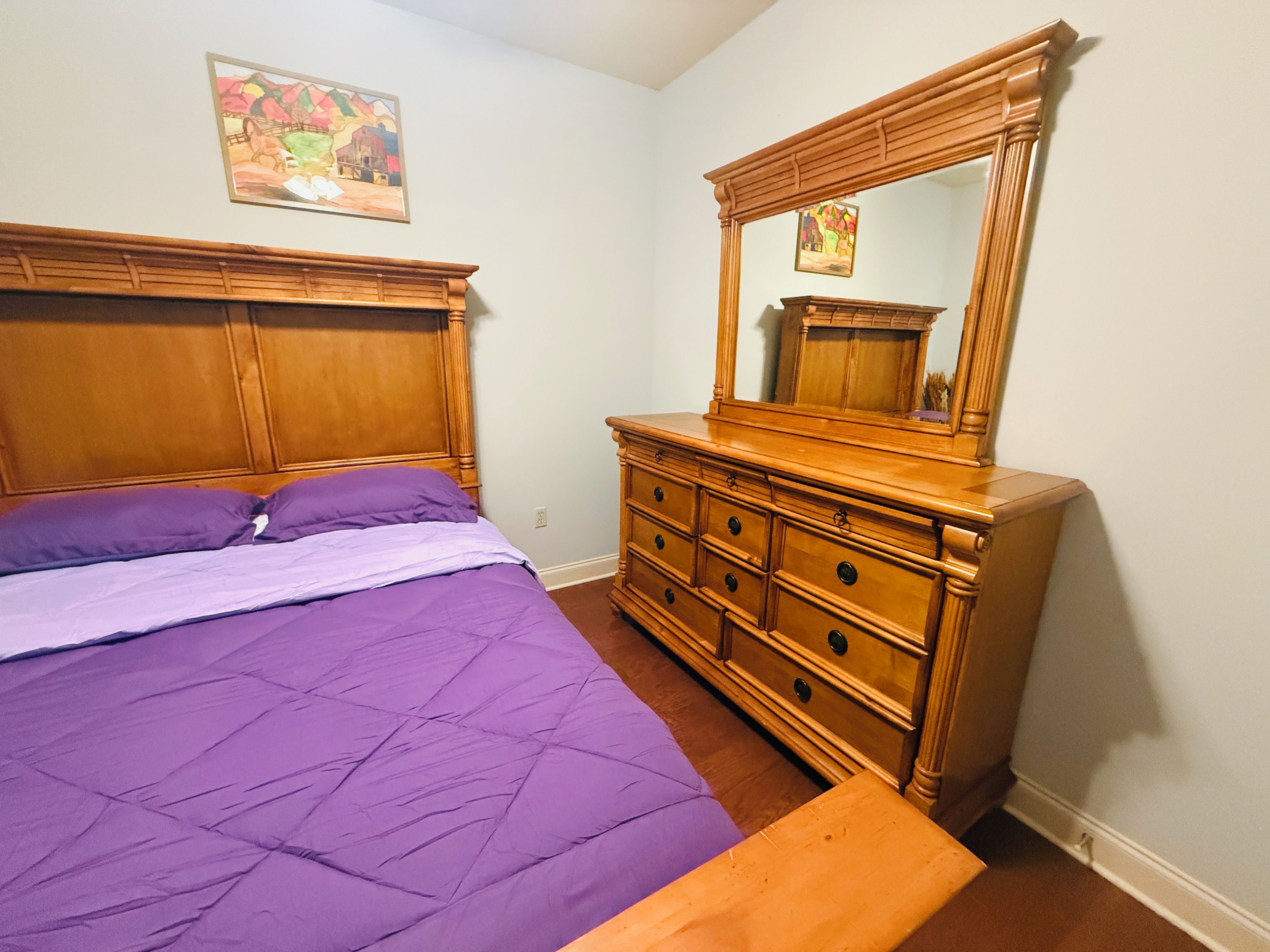 A bedroom with a bed, a dresser, and a mirror.