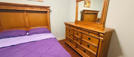A bedroom with a bed, a dresser, and a mirror.