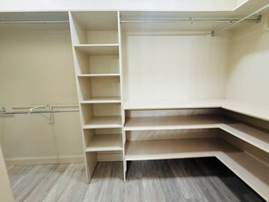 A room with a built-in closet featuring multiple shelves and hanging space.