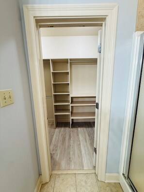 A walk-in closet with multiple shelves and a door.