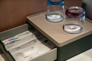 A drawer with packets, two glasses with lids, and a wooden background.
