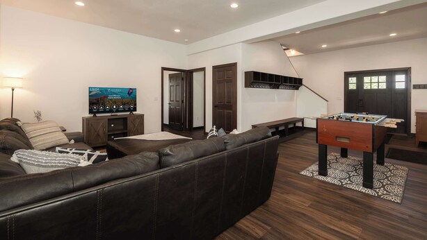 A modern living room with a leather sofa, a foosball table, and a flat-screen TV mounted on the wall. - Mountain Retreat at the Base of Granby Ranch (Granby)