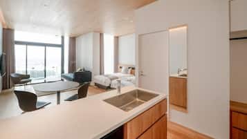 A modern kitchen with a built-in dishwasher, a dining area with a round table and chairs, and a large window providing a view of the city.