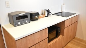 Una cocina compacta equipada con microondas, tostadora, cafetera y un lavamanos pequeño.