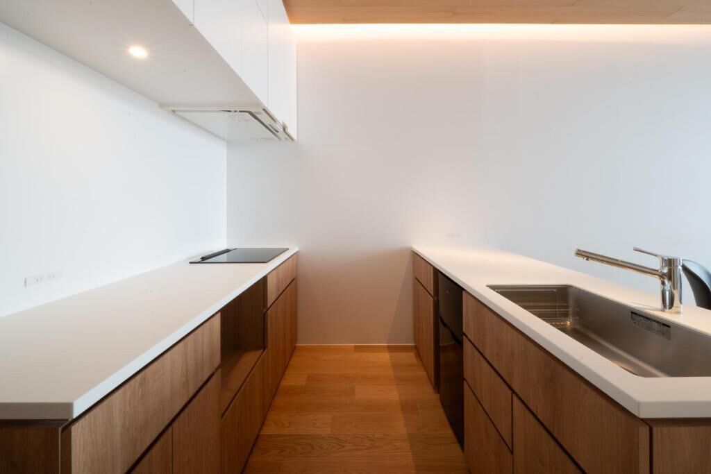 A modern kitchen with white cabinetry, a wooden countertop, and a stainless steel sink.