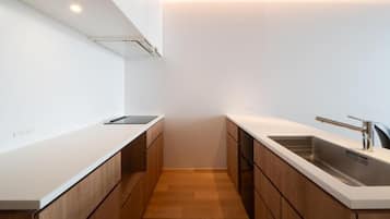 A modern kitchen with white cabinetry, a wooden countertop, and a stainless steel sink.