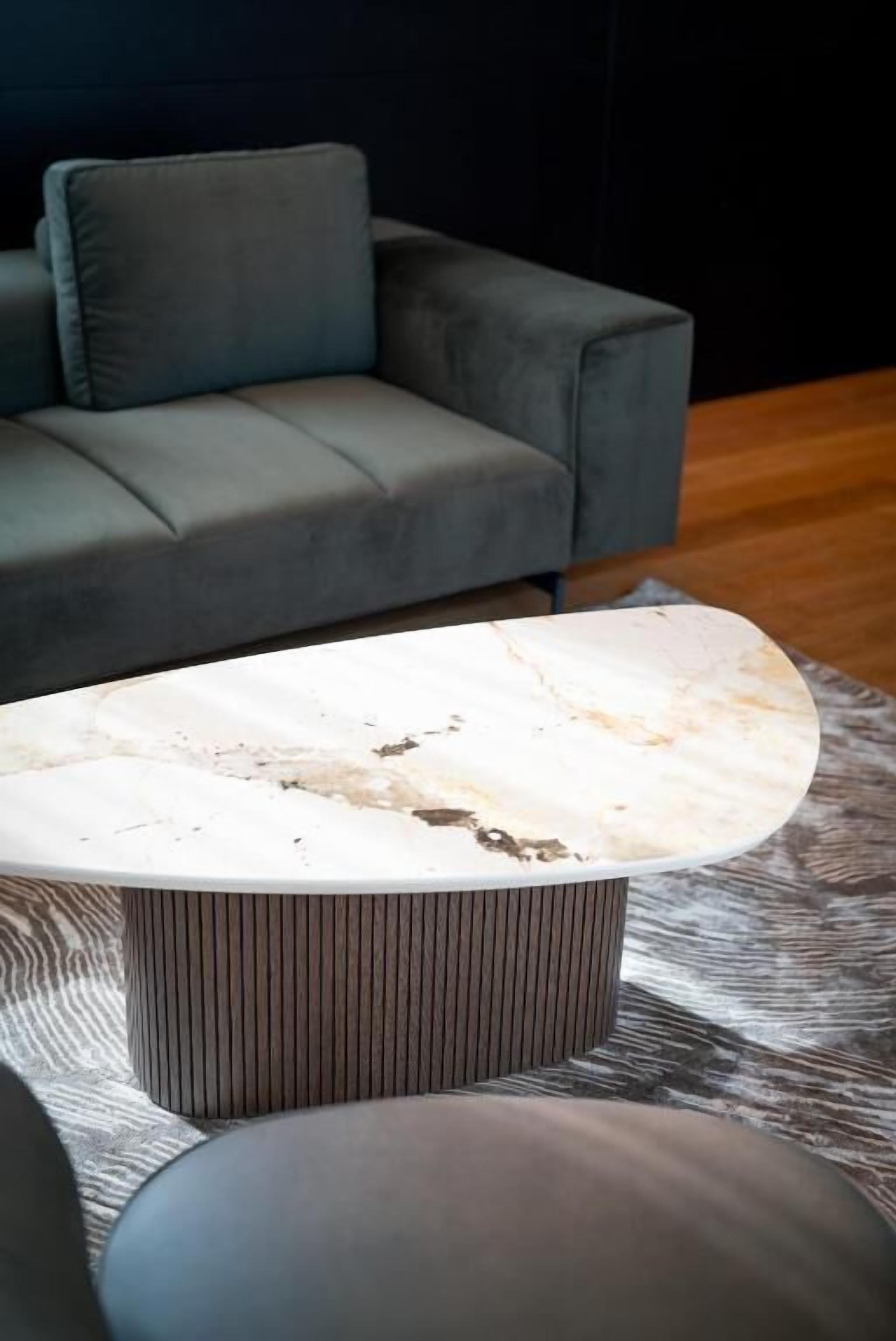 Una sala de estar moderna con un sofá gris y una mesa de centro de mármol.