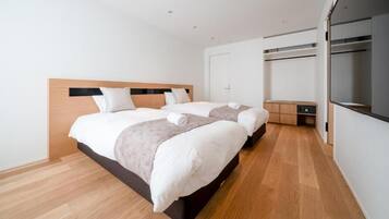 Quarto de hotel com duas camas, um guarda-roupa e uma pequena escrivaninha.